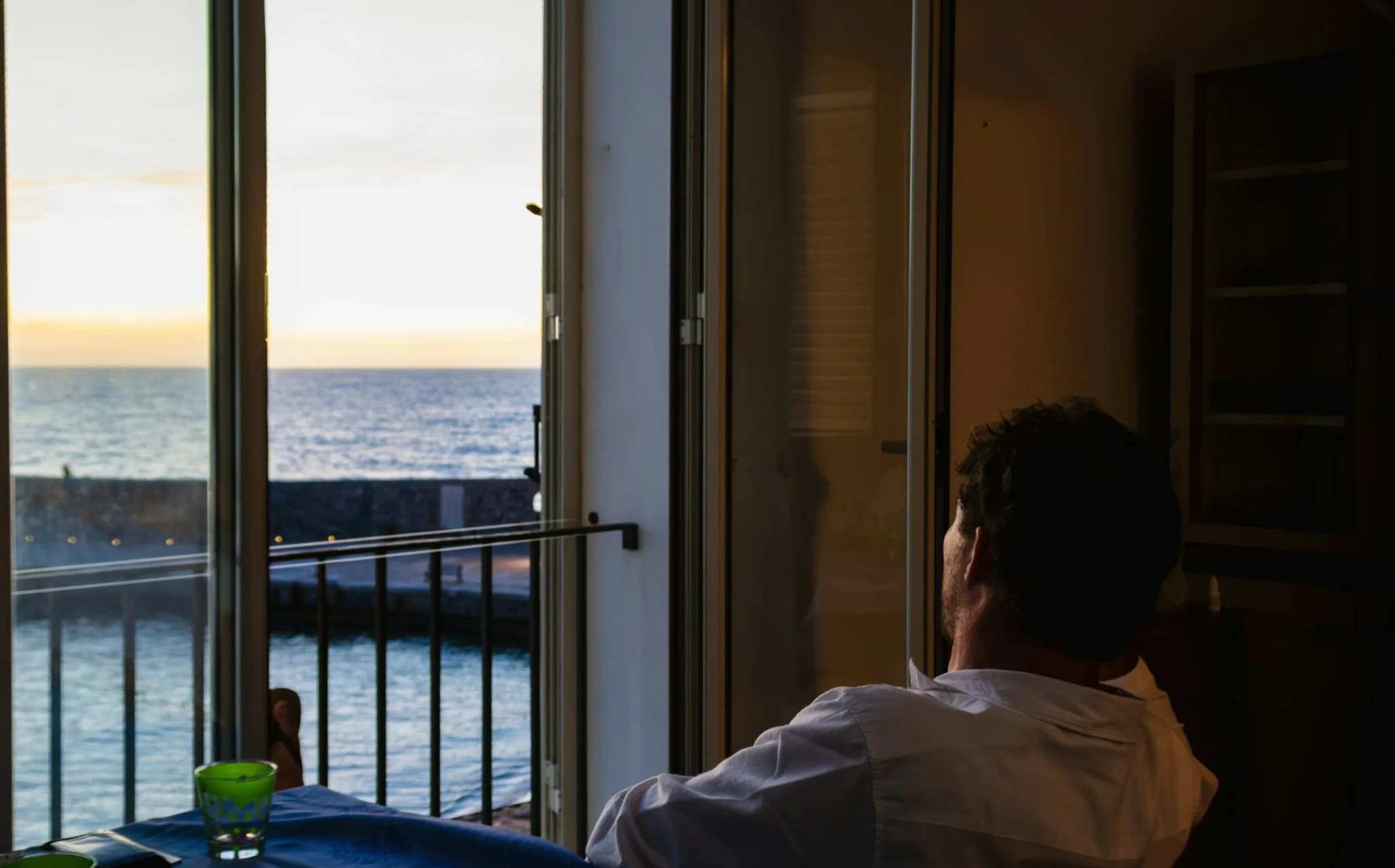 A man sitting by the window looking at the sea