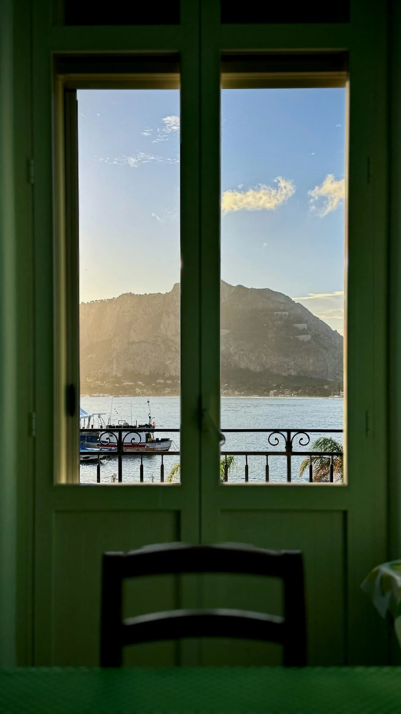 A window with green frames looking out to sea