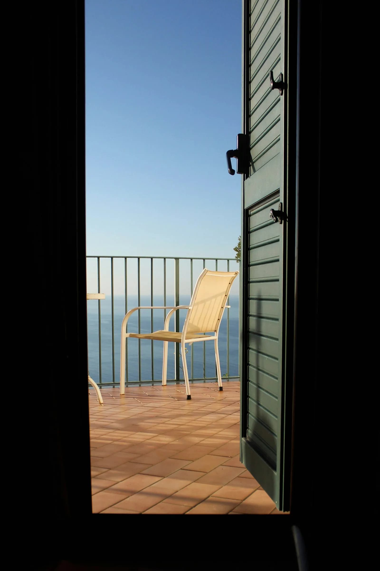 A French window open onto the balcony and the sea