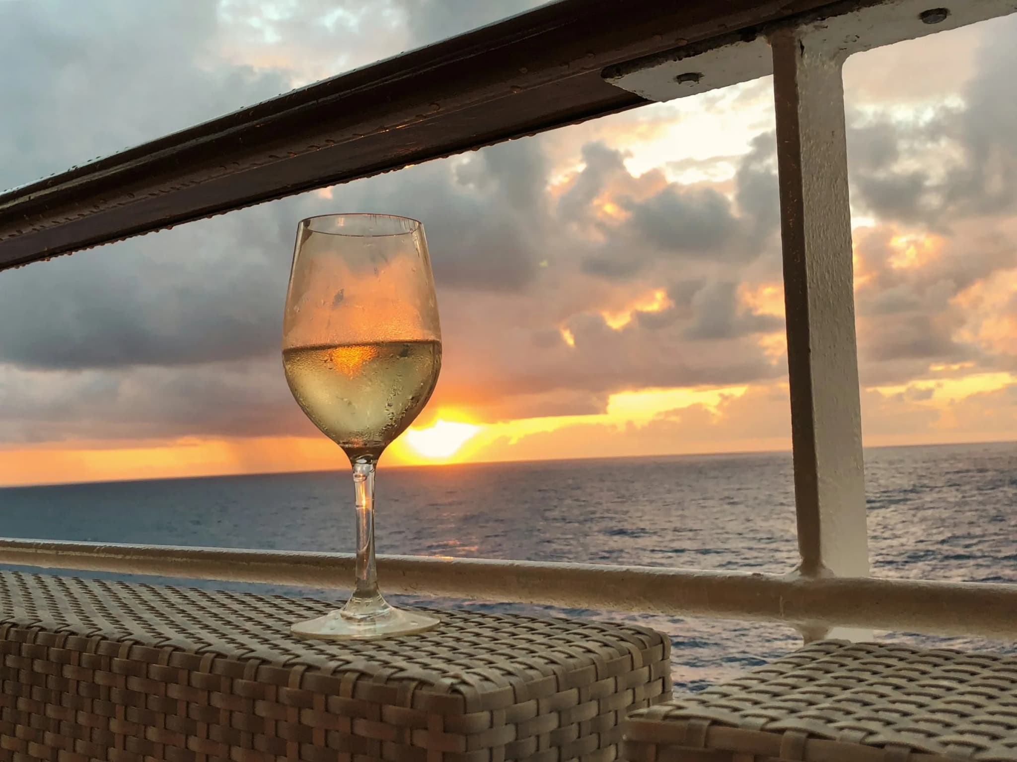 A glass of white wine against the sunset, from the deck of a boat