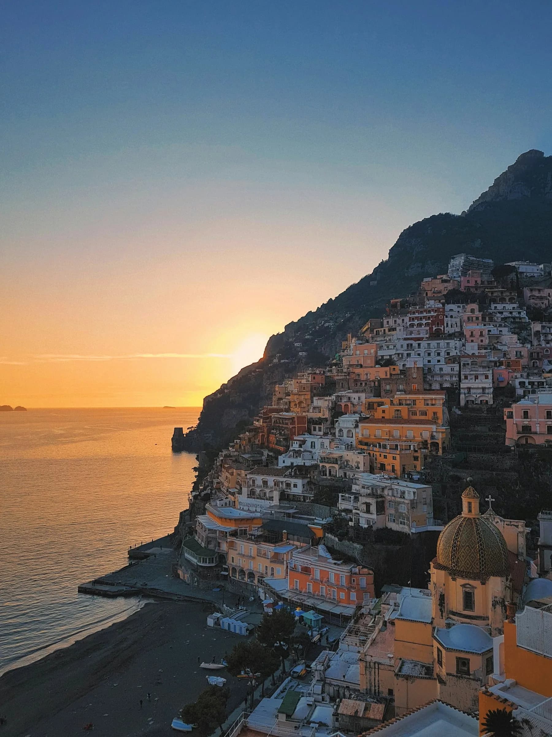 Il sole che scende dietro Positano, con la cupola di Santa Maria Assunta in basso