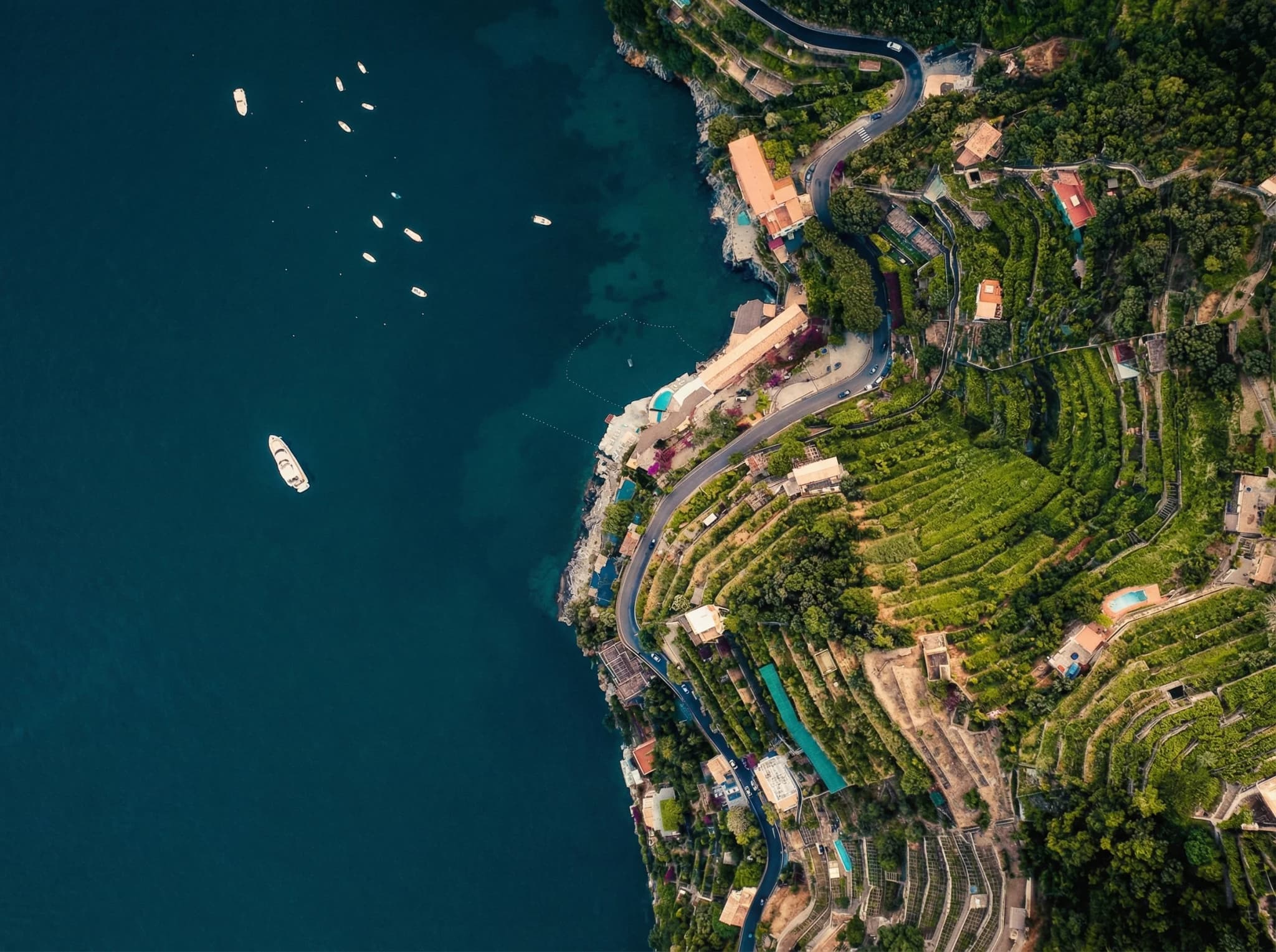 The coast seen from above: the cliff road, the terraced gardens and the boats at anchor
