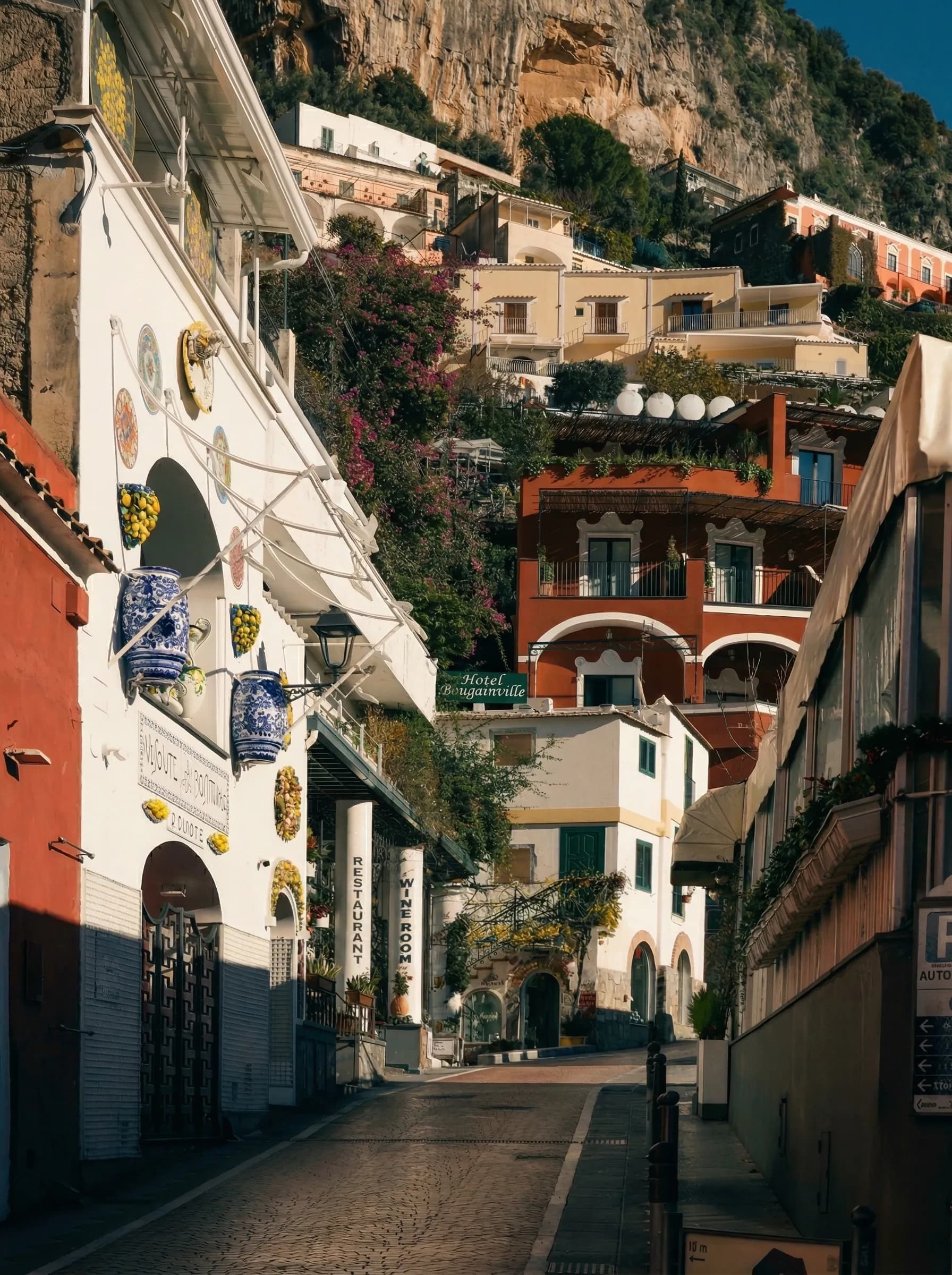 Un vicolo di Positano nell'ombra del mattino, con il sole ancora solo sulle case in alto